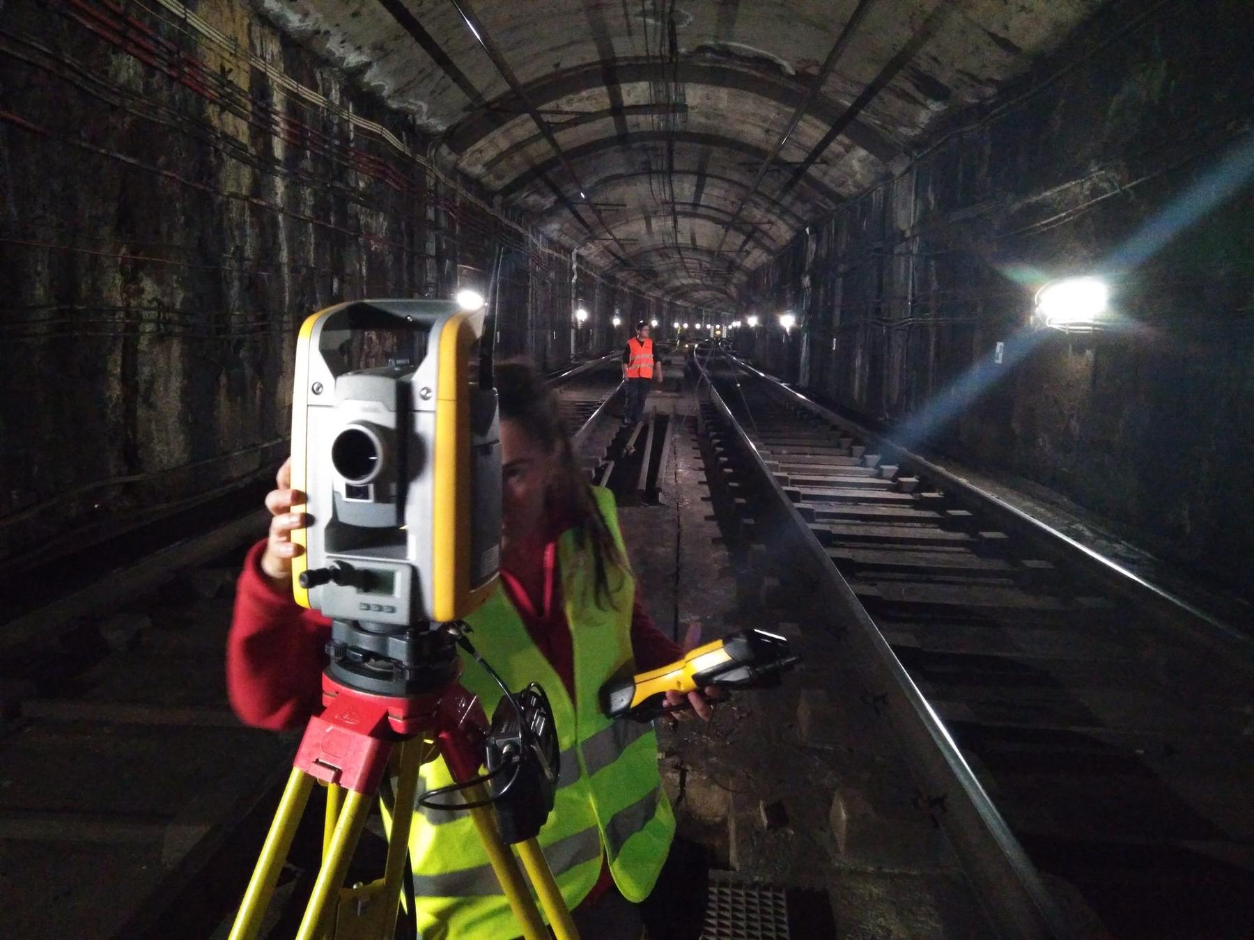 Topògrafa mesurant amb estació total dins d'un túnel de metro